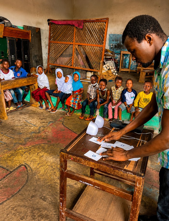 A teacher laying out letter cards while a class of children watches