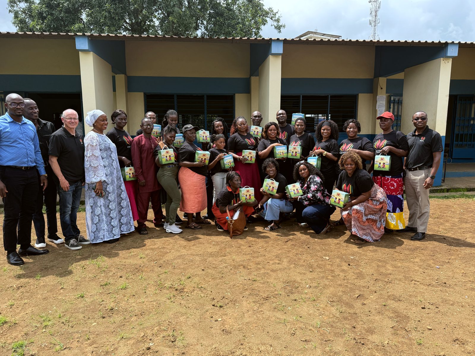Newly trained teachers holding Doctrina reading kits outside their school