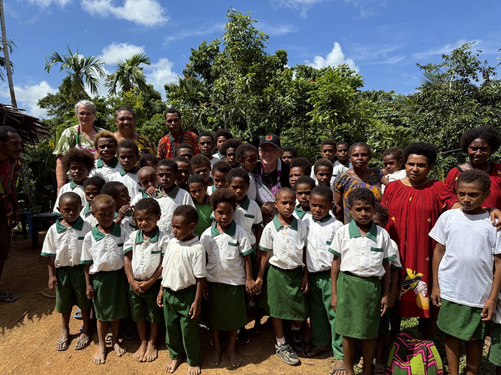 Children in uniform with their mothers and teachers outside a Mum's Preschool