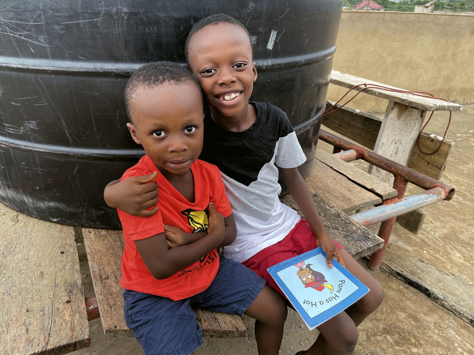 An older brother holding his reading book with his younger brother under his arm